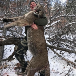 A man posing with the mountain lion he harvested in Colorado.