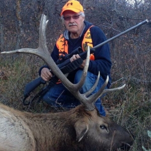 A gentleman posing with the elk he harvested during his Colorado hunt.
