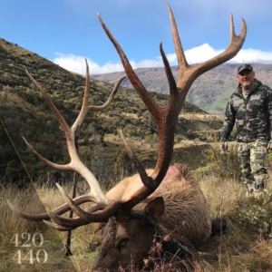 Man posing next to the 420-440 score red stag he harvested during his New Zealand hunt.