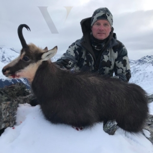 A man posing with the chamois he harvested on his New Zealand hunt.