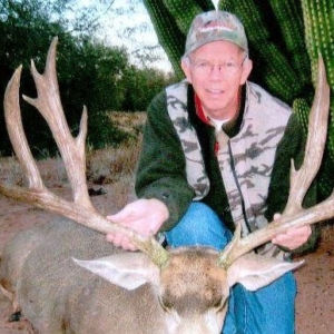 Man posing in front of cactuses with the deer he harvested during his Sonora, Mexico hunt.