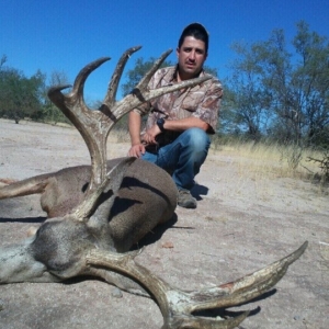 A man posing with the large mule deer he harvested on his hunt in Sonora.