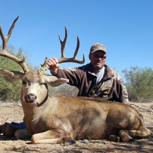 A man holding the horns of the large 10-point mule deer he harvested in Sonora, Mexico.