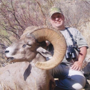 A man posing with the large desert bighorn he harvested during his hunt in Sonora, Mexico.
